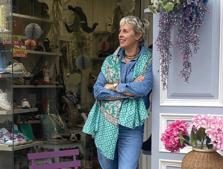 Femme devant une boutique de chaussures à Salernes, entourée de sacs et accessoires