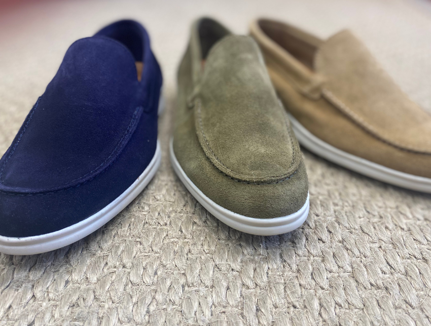 Mocassins homme en daim bleu, vert et beige avec semelle blanche, posés sur un tapis naturel